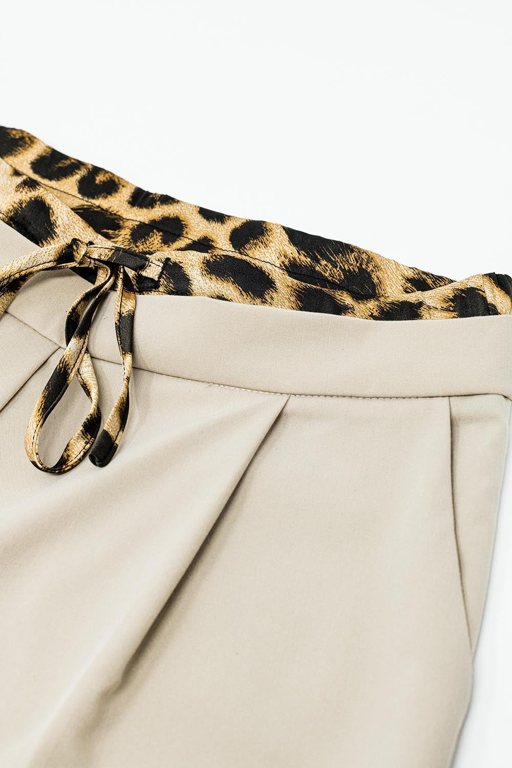 Calças compridas bege plissadas com pormenor de leopardo na cintura