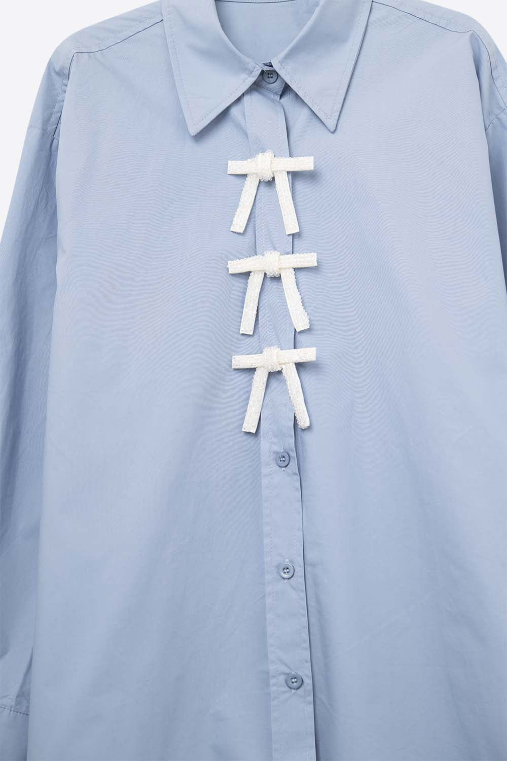 Camisa de popelina azul de tamanho grande com botões de laço brancos com brilhantes