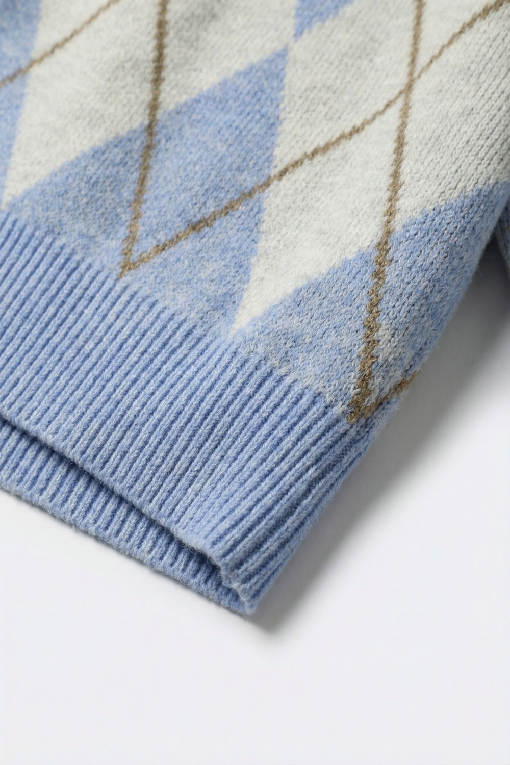 Camisola de malha azul com padrão de losangos e gola polo.