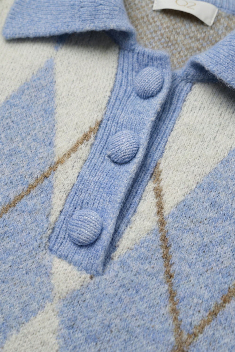 Camisola de malha azul com padrão de losangos e gola polo.