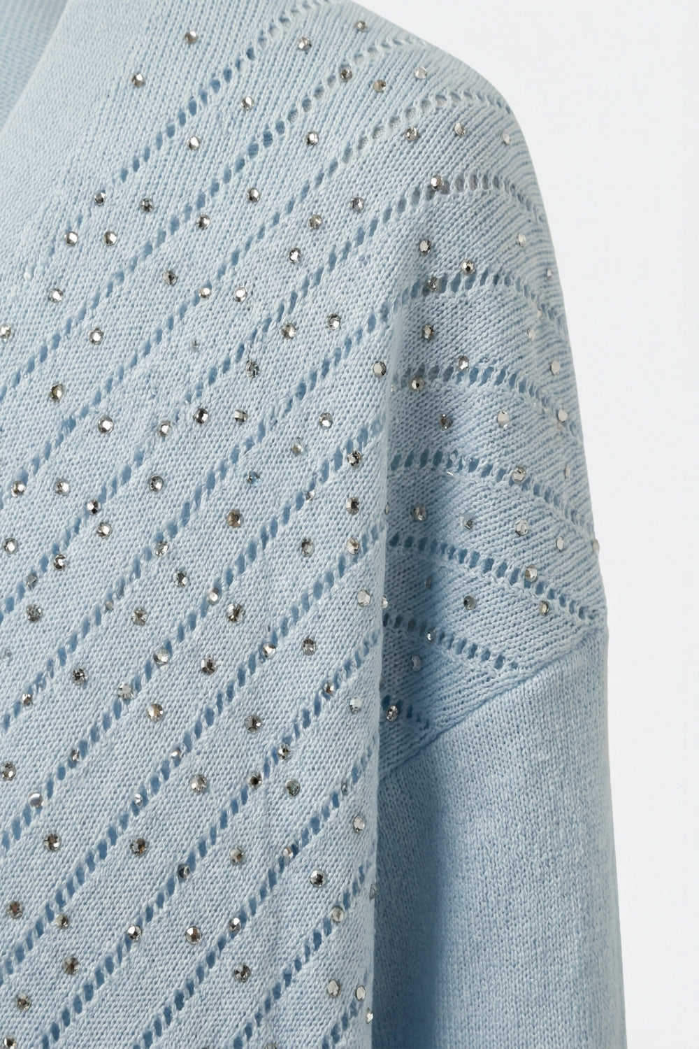 Camisola de malha azul clara com decote em V e pormenores brilhantes