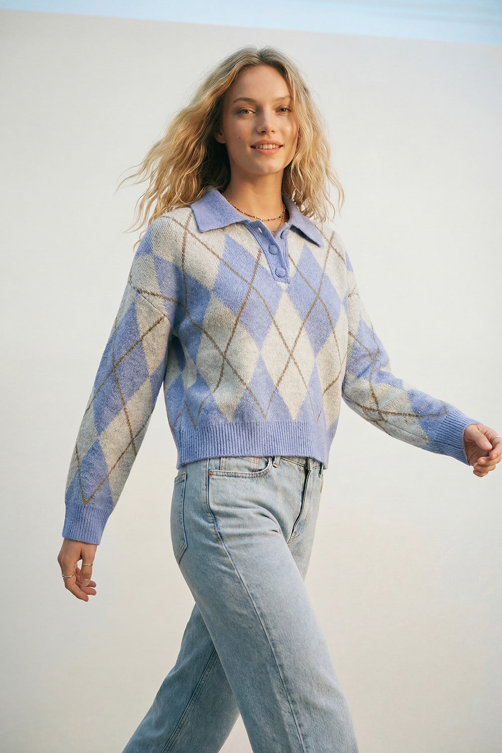 Camisola de malha azul com padrão de losangos e gola polo.