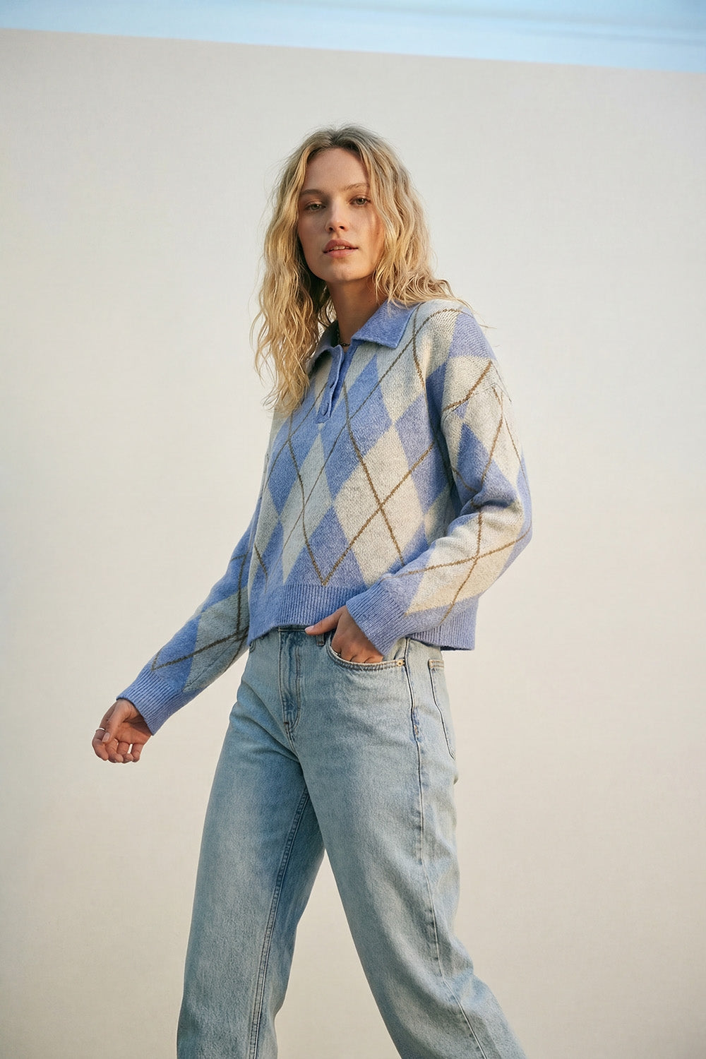 Camisola de malha azul com padrão de losangos e gola polo.