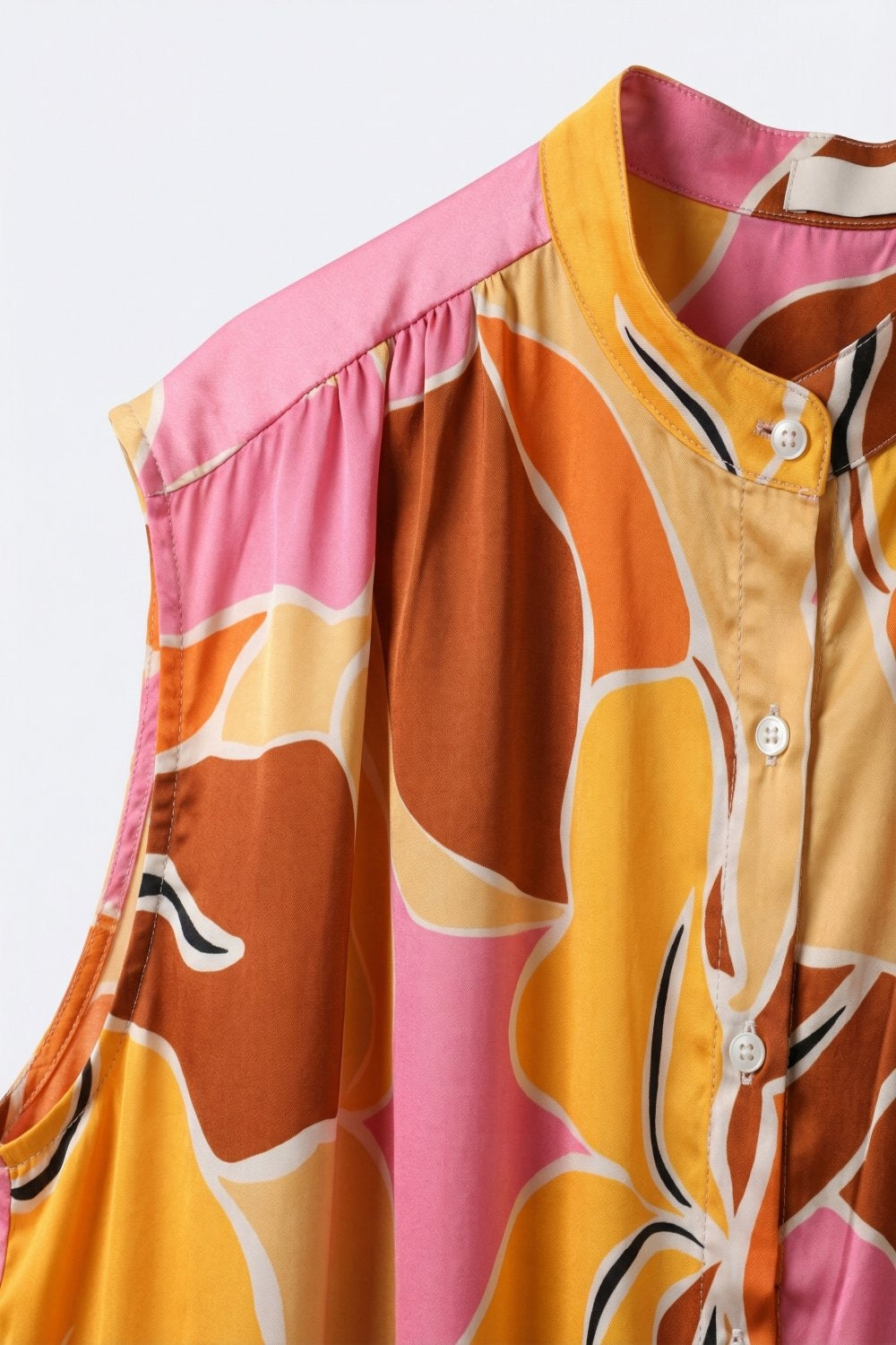 Blusa sem mangas com estampa tropical e botões frontais em tons quentes de laranja.