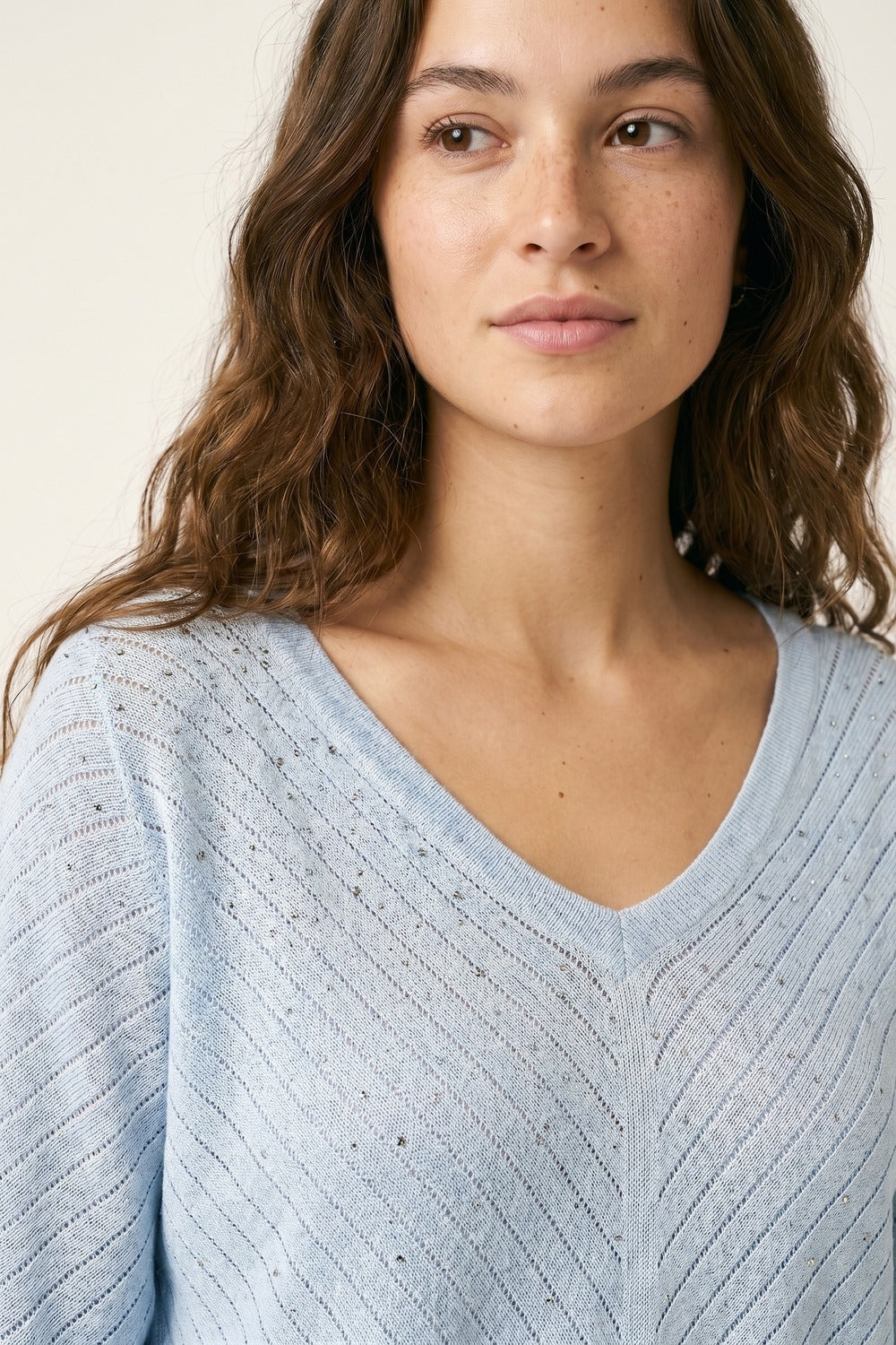 Camisola de malha azul clara com decote em V e pormenores brilhantes
