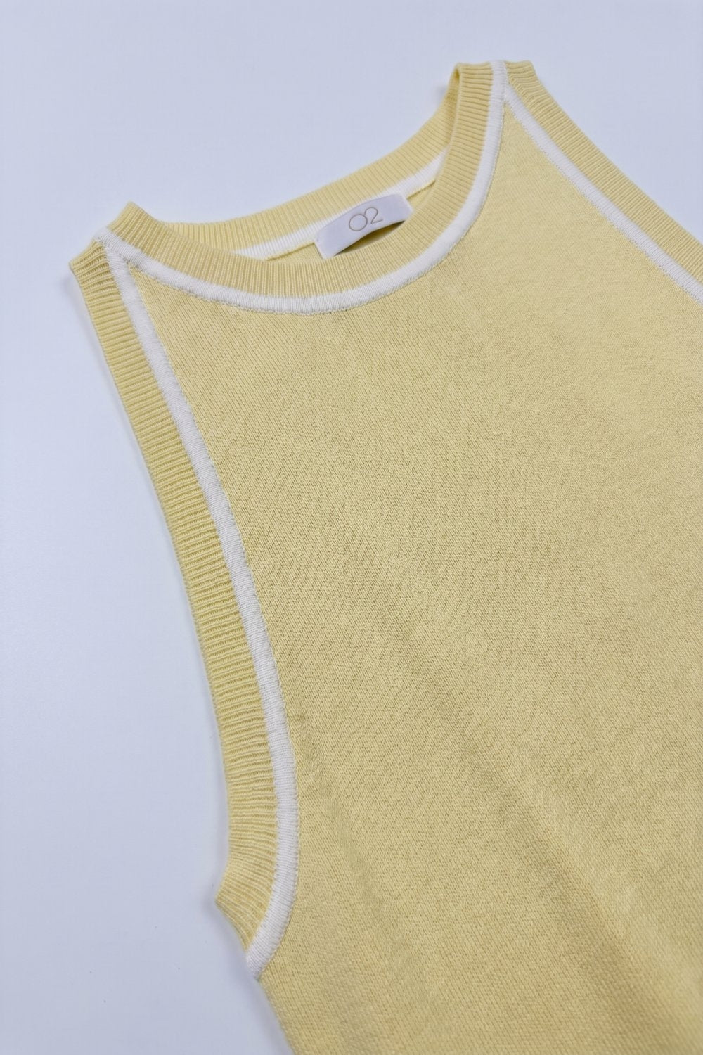 Top de malha sem mangas em amarelo manteiga com detalhes de linhas brancas