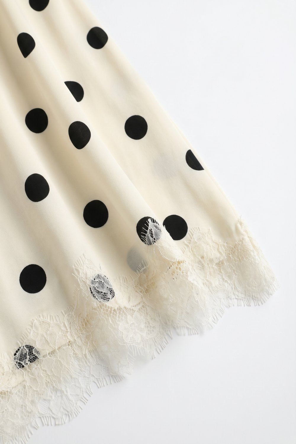 Saia midi assimétrica de cetim com padrão de bolinhas em creme e guarnição de renda