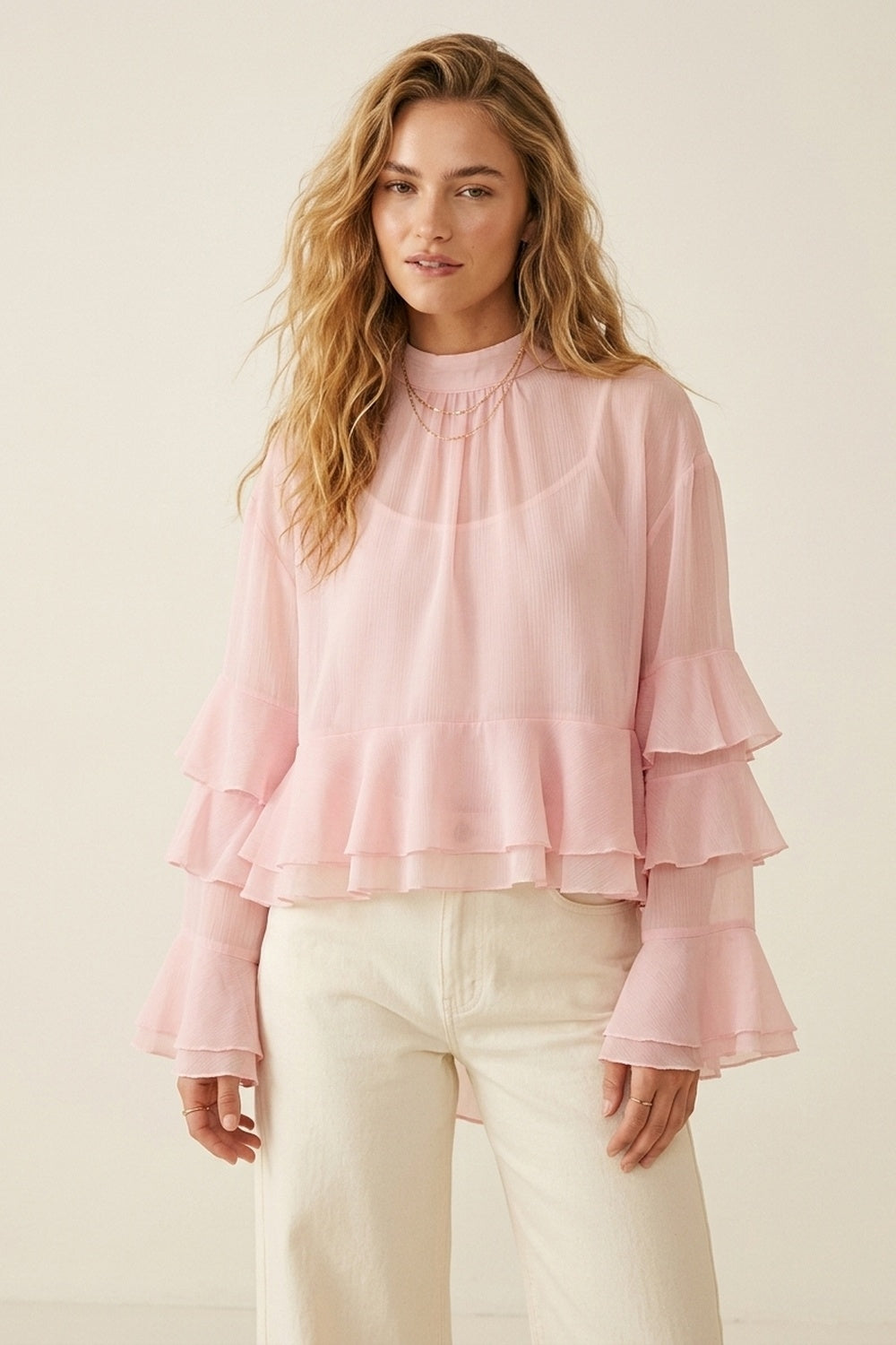 Blusa assimétrica de chiffon rosa claro com folhos em camadas e gola alta.