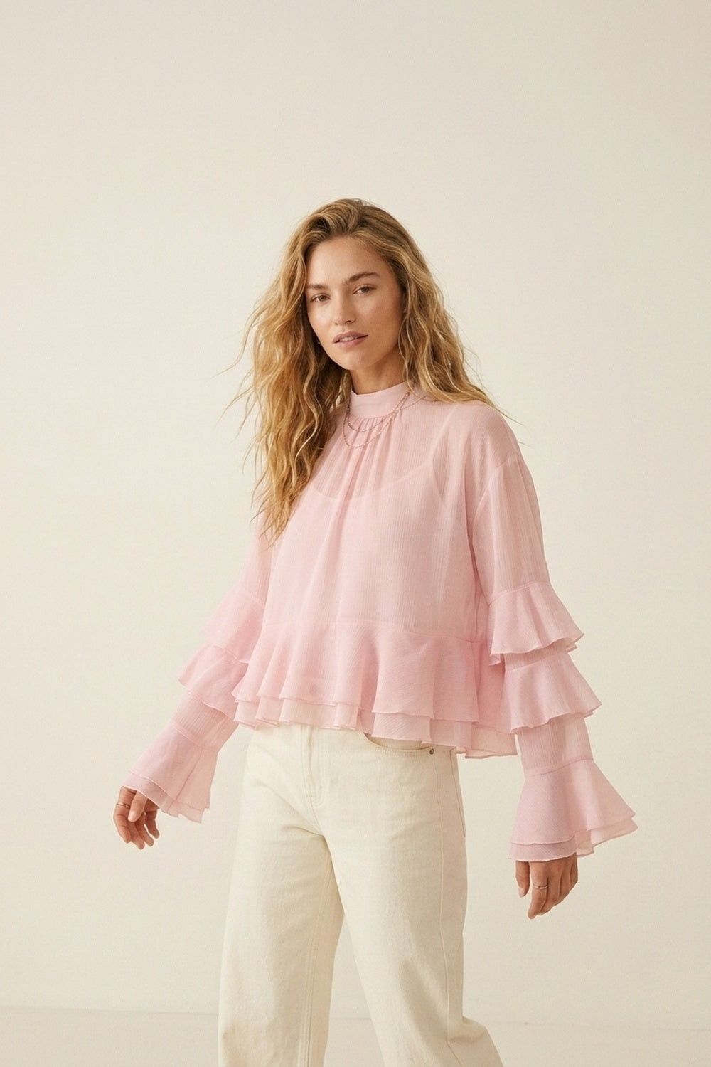 Blusa assimétrica de chiffon rosa claro com folhos em camadas e gola alta.