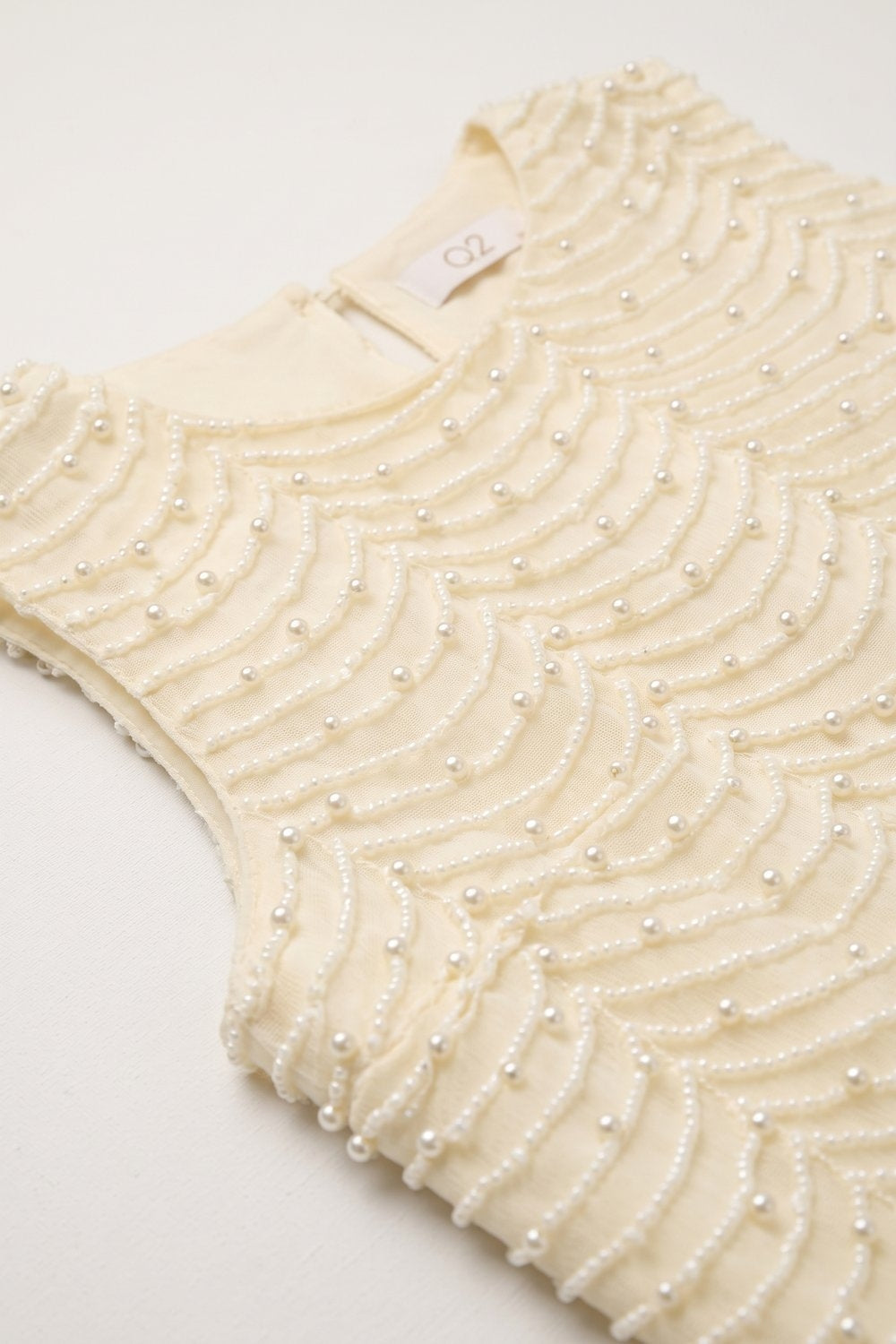 Blusa sem mangas com barra em vieira adornada com miçangas na cor creme