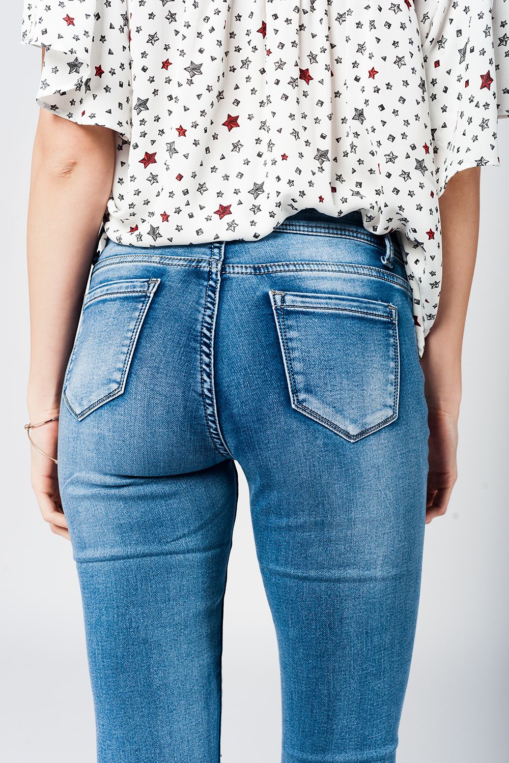 Jeans apertados com baixa joelho lavagem média desgastado e quebrado