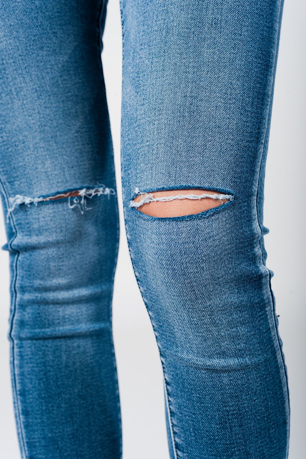 Jeans apertados com baixa joelho lavagem média desgastado e quebrado