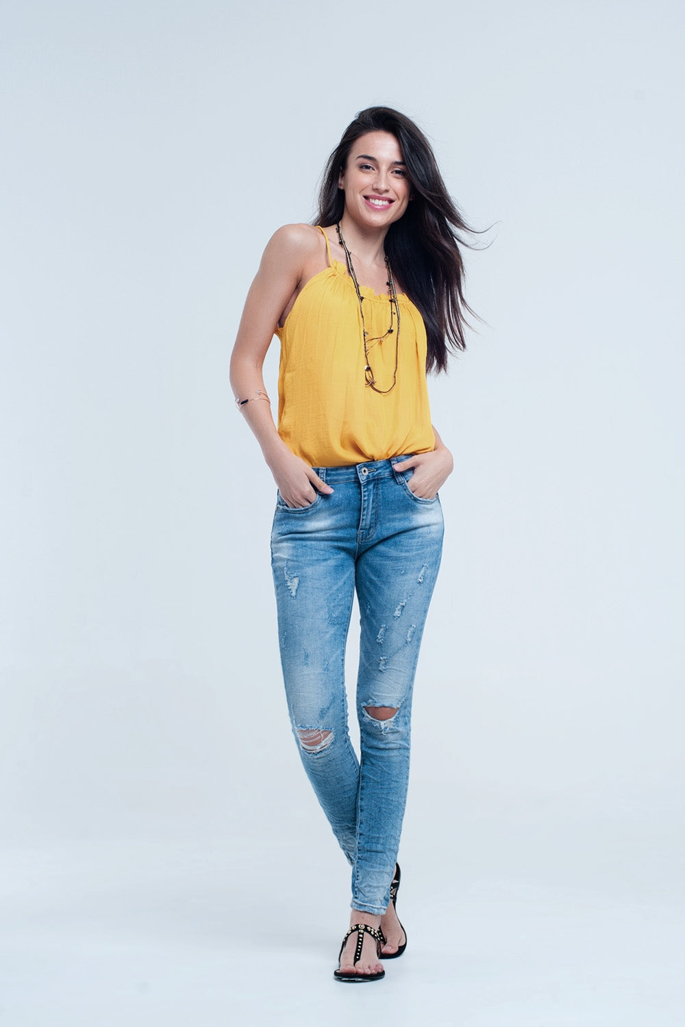 Calça jeans skinny no meio da lavagem com os joelhos rasgados