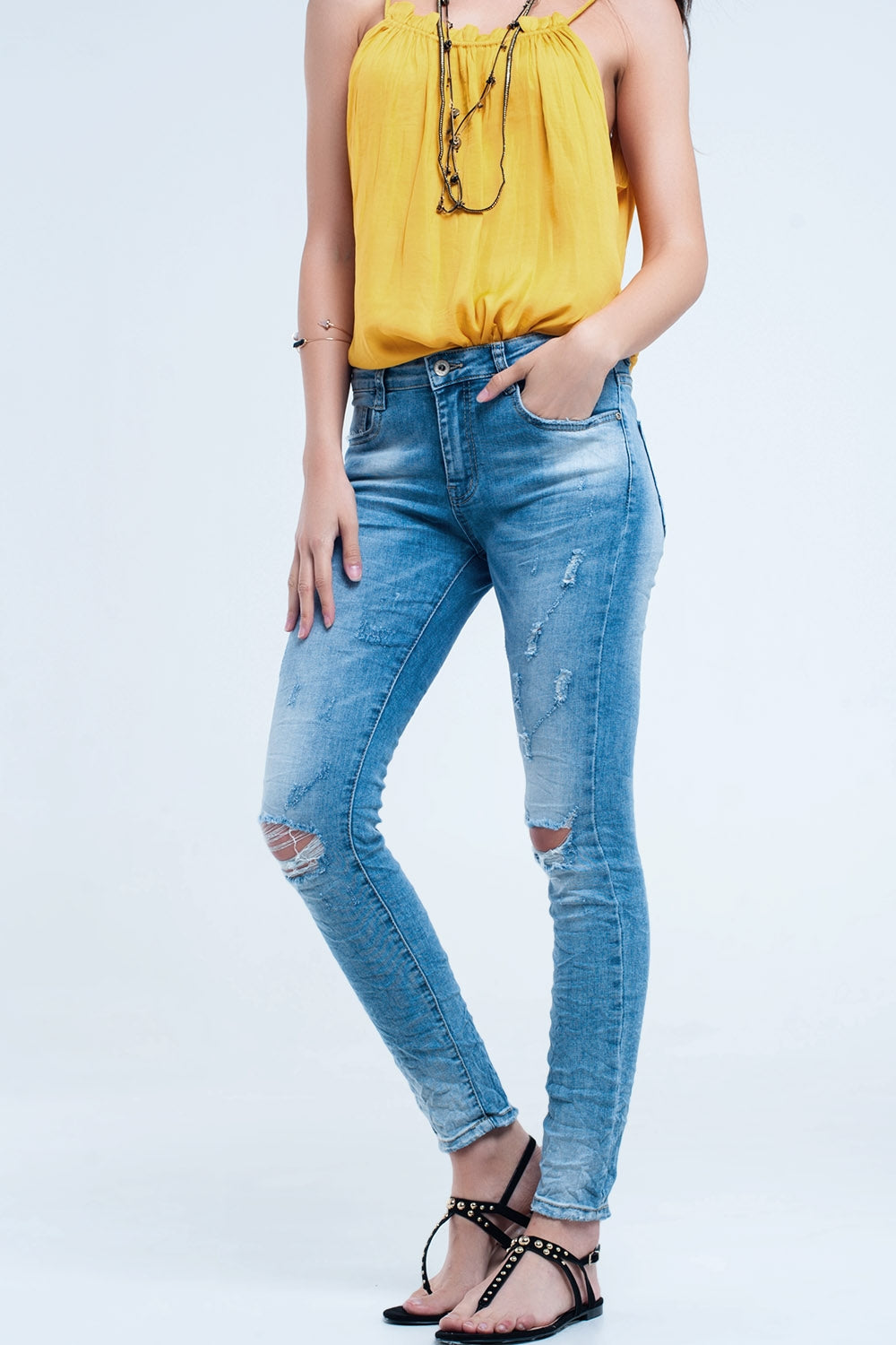 Calça jeans skinny no meio da lavagem com os joelhos rasgados