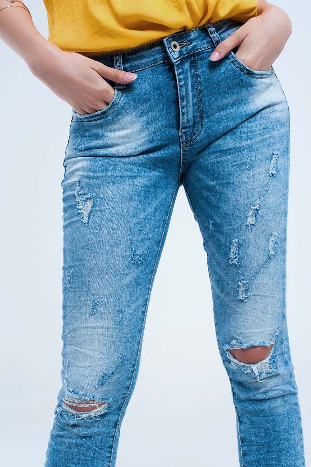 Calça jeans skinny no meio da lavagem com os joelhos rasgados