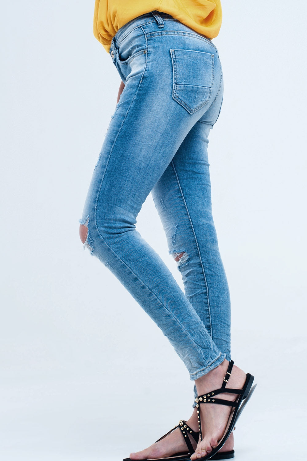 Calça jeans skinny no meio da lavagem com os joelhos rasgados