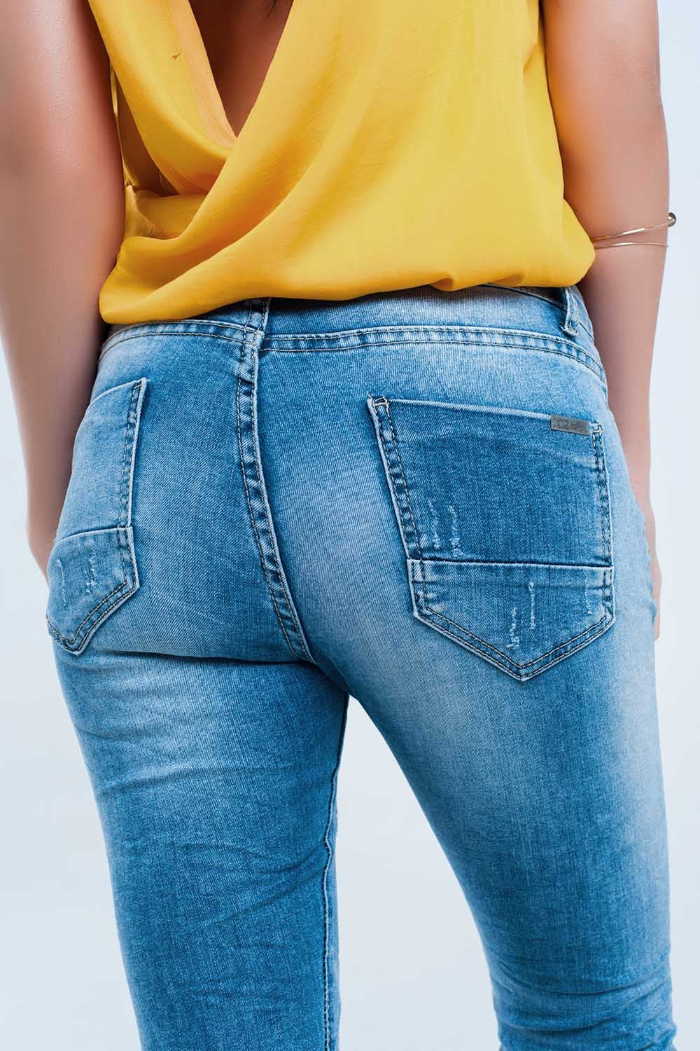 Calça jeans skinny no meio da lavagem com os joelhos rasgados