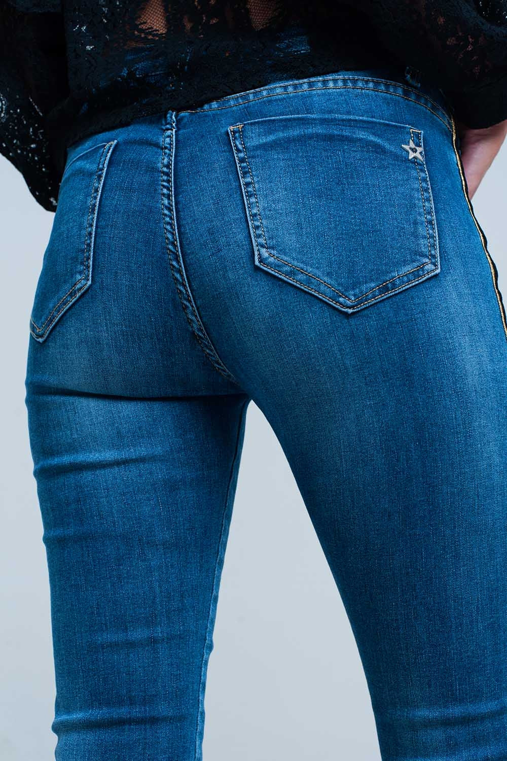 Calças de ganga azul com faixa lateral dourada e preta