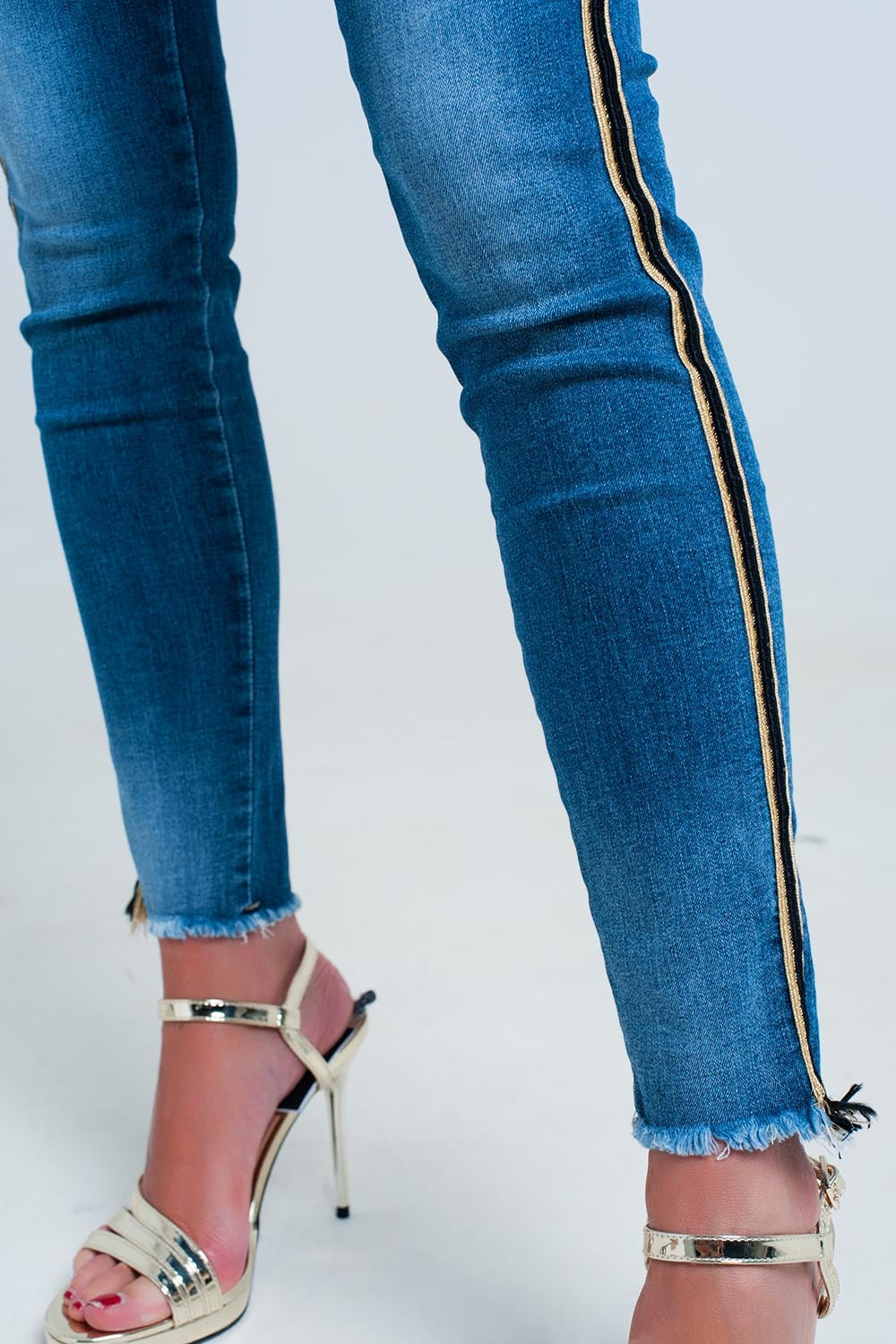 Calças de ganga azul com faixa lateral dourada e preta