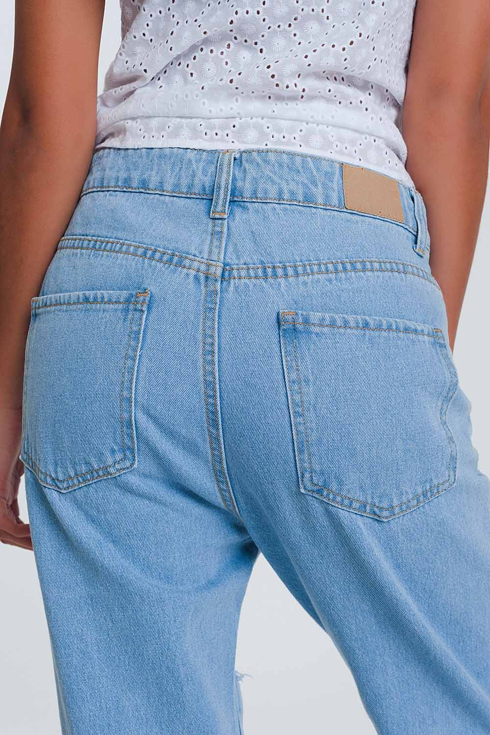 Jeans azul claro de cintura alta com rasgos nos joelhos