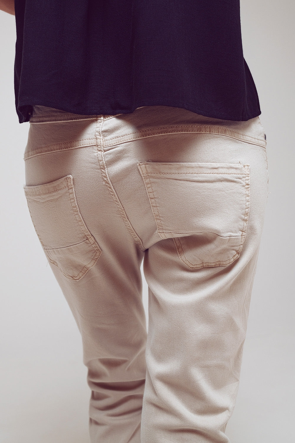 Calça jeans skinny com botões expostos em bege