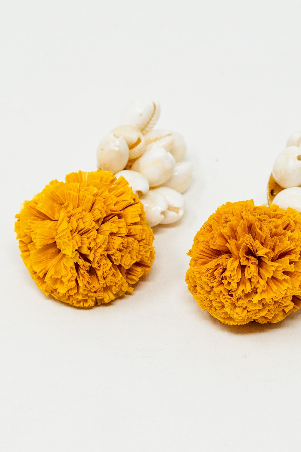 Brincos com conchas creme e pompons amarelos