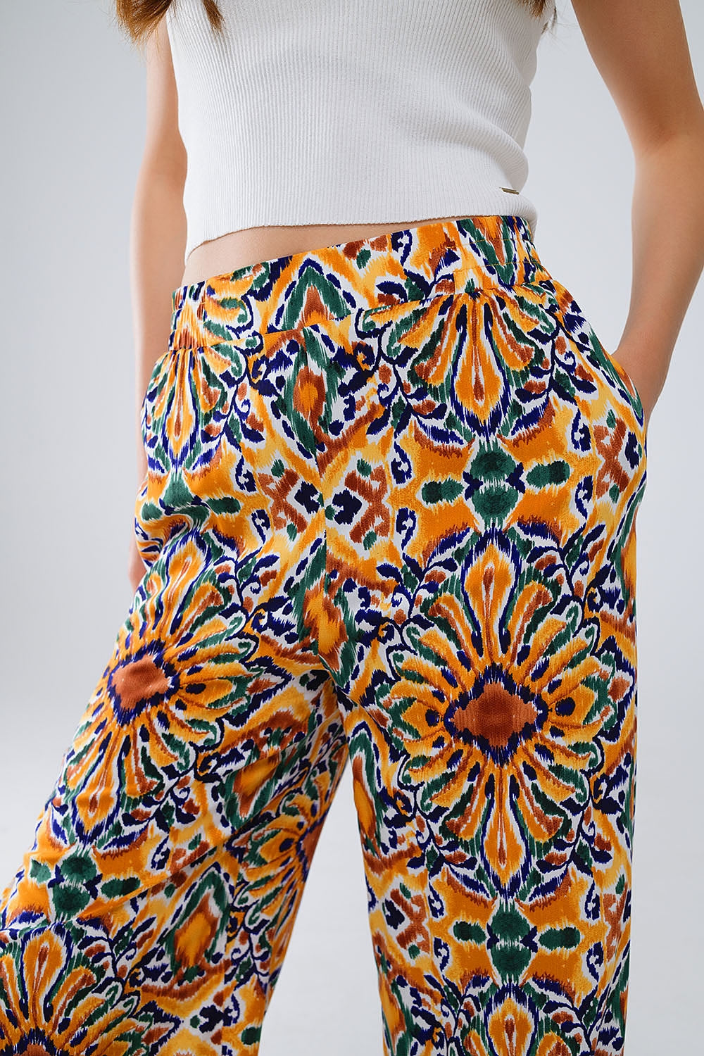 Calças multicoloridas com estampado de flores em laranja e azul