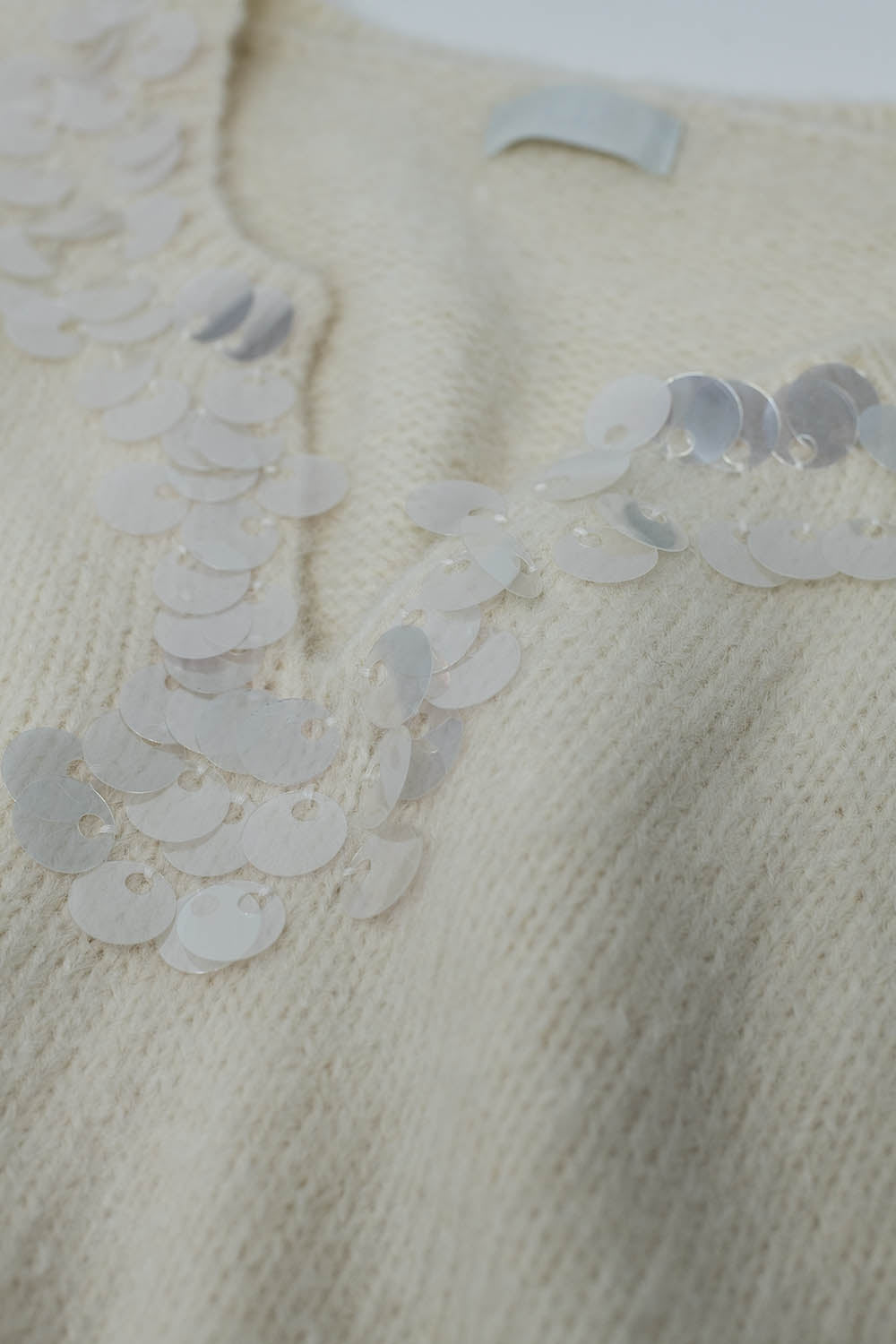 Suéter creme de decote em V com detalhe de lantejoulas